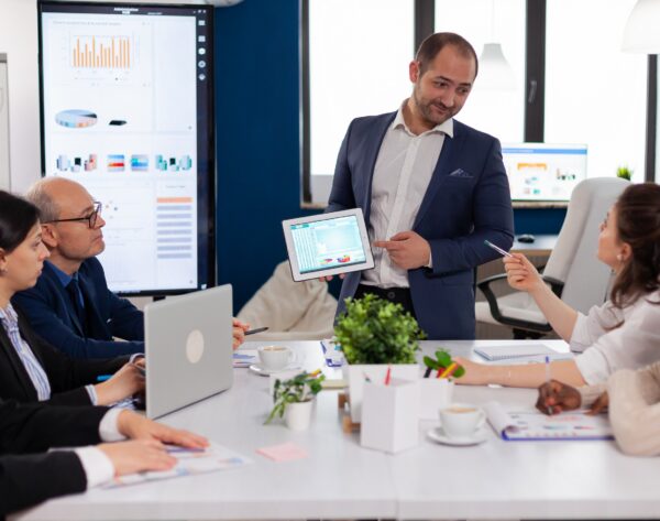 Company leadership explaining briefing project in conference room to team. Project leader discussing with teamworkers in broadroom, analysing charts, graphs, financial evolution of company.